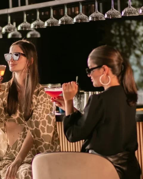 Dos mujeres disfrutando cócteles en la barra de Etro Rooftop de Binn Hotel en Medellín.