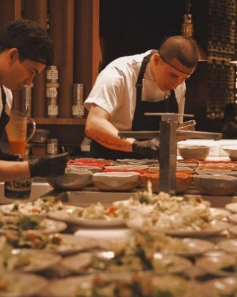 Dos hombres con delantales blancos preparando comida en un restaurante, reflejando la elegancia de eventos en el BINN Hotel