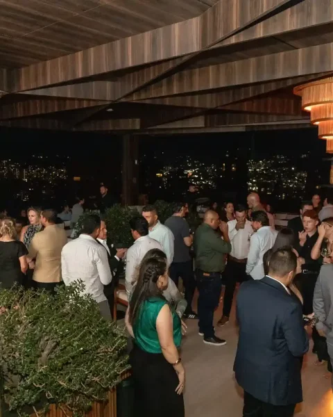 Empleados celebrando una fiesta de fin de año de empresa en la terraza nocturna de Etro Rooftop con vista a la ciudad.