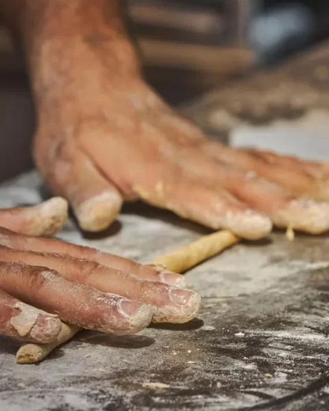 Manos formando tiras de masa fermentada sobre mesón enharinado en La Makha, Medellín