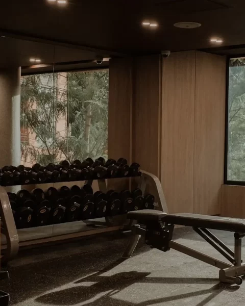 Gimnasio B GYM en Binn Hotel Medellín con zona de pesas, bancos de entrenamiento y grandes ventanales.
