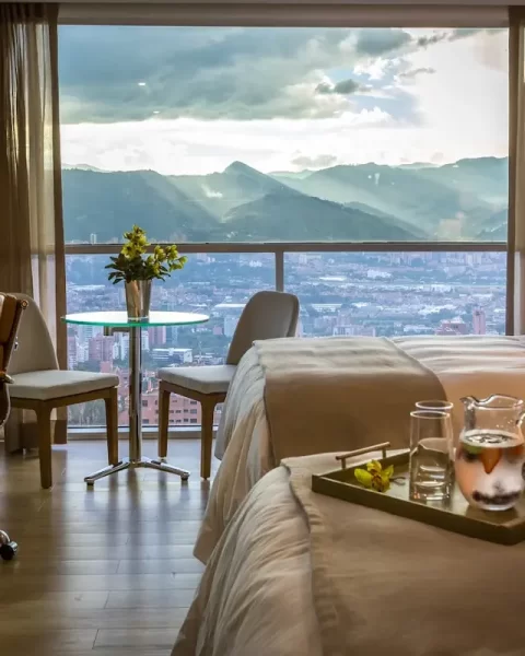 Habitación doble de Binn Hotel Medellín con ventanal, escritorio y vista panorámica a la ciudad y montañas