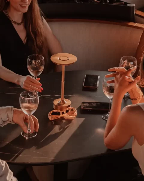 Grupo de amigos disfrutando de bebidas durante la hora dorada alrededor de una mesa iluminada en Etro Rooftop Medellín.