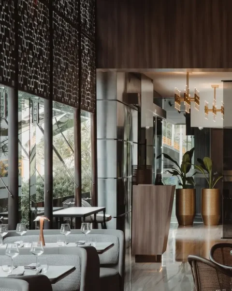 Salón principal del restaurante La Makha en El Poblado con mesas elegantes, iluminación moderna y ventanales hacia la vegetación exterior.