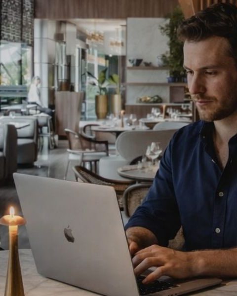 Nómada digital trabajando en su laptop desde el restaurante La Makha en Medellín, disfrutando de un ambiente sofisticado ideal para el trabajo remoto de lujo.