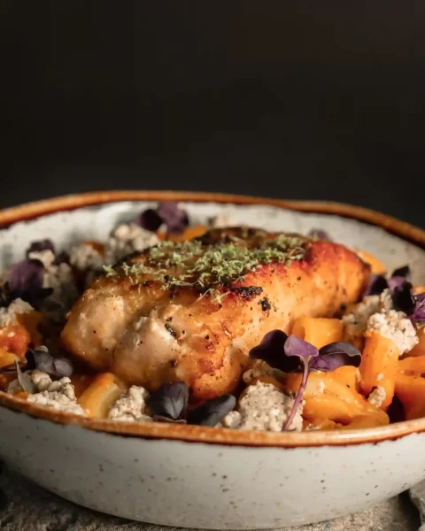 Bowl de pasta con proteína sellada, ricotta y flores moradas del menú del Día del Padre en La Makha
