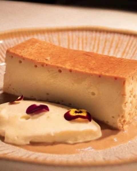 Un trozo de cheesecake cremoso sobre un plato blanco, listo para disfrutar con la playlist perfecta de La Makha