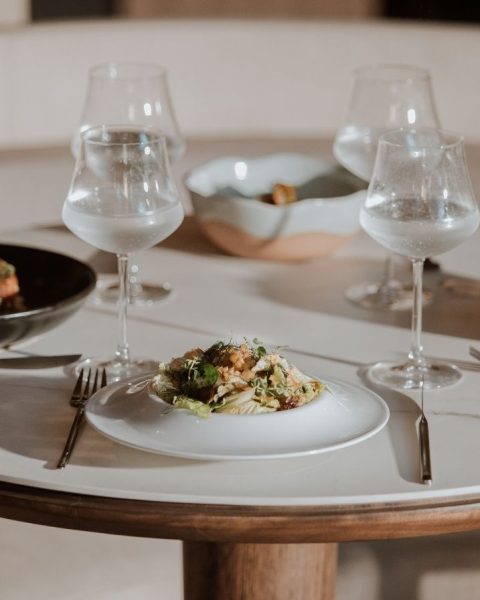 A table set with two elegant plates and glasses, showcasing luxury dining plans in Medellín