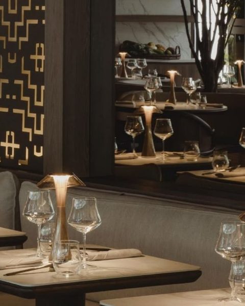 Mesas elegantemente servidas con copas de cristal y lámparas de diseño en el salón principal de La Makha.