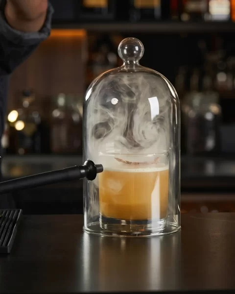 Mocktail premium bajo campana de humo en la barra de La Makha, Medellín