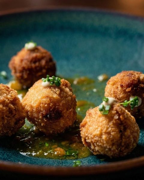 Croquetas vegetarianas gourmet servidas en Etro Rooftop Medellín con salsa verde y presentación elegante en plato moderno.