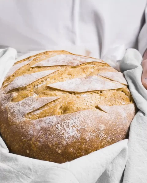 Chef sosteniendo hogaza de pan de masa madre con trigos ancestrales en La Makha, Medellín