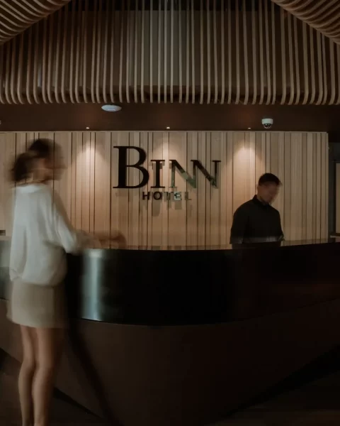 Front desk reception counter in the lobby of Binn Hotel Medellin with the logo on a wooden wall