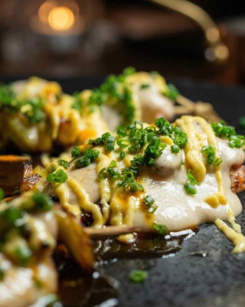 Plato de comida fusión gourmet en rooftop de Medellín con presentación moderna y ambiente nocturno elegante