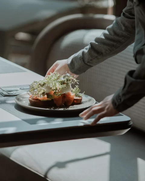 Mesero sirviendo tostada de salmón con huevo pochado y microgreens en La Makha, Medellín