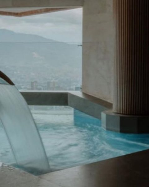 Cascada en un baño del hotel BINN, con vistas a las montañas, creando un ambiente de spa de lujo