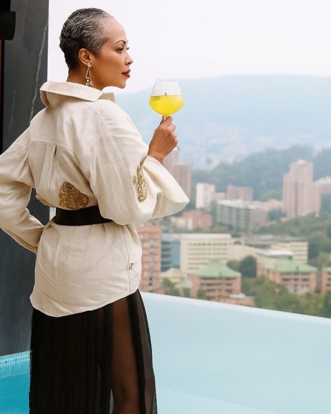 Mujer en bata blanca sosteniendo una copa de vino durante el atardecer en una sesión de afterwork.