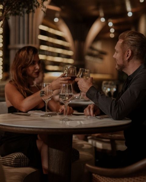 Dos personas levantando copas de vino en un restaurante lujoso de Medellín