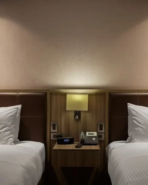 Two twin beds with crisp white linens and an illuminated nightstand in a room at Binn Hotel Medellin