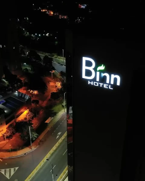 Fachada nocturna y logo iluminado de Binn Hotel Medellín: vista aérea de la ubicación estratégica en El Poblado.