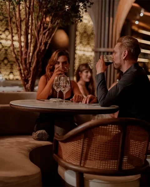 Visitantes disfrutando una copa de vino en una mesa íntima de Etro Rooftop.